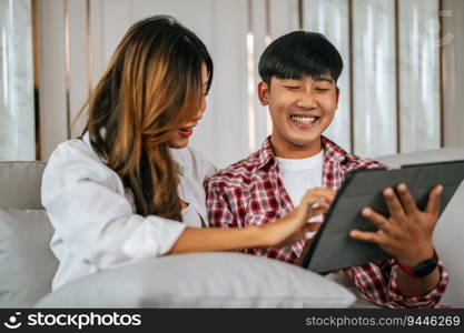 Happy Young couple sitting on sofa in living room at home use tablet with happiness together, happy family concept