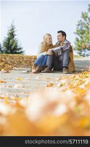 Happy young couple sitting on steps in park