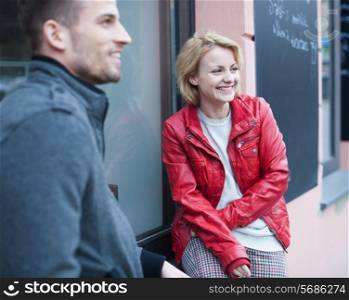 Happy young couple sitting outside cafe