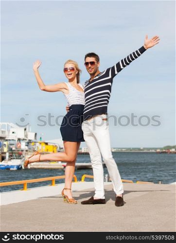 happy young couple standing and waving in port