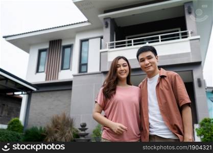 happy young couple standing outside their house