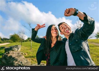 Happy young couple taking a selfie with a smartwatch outdoors. Couple taking a selfie with a smartwatch