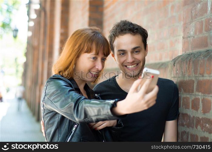 Happy young couple taking selfie with mobile phone in the city. Fun concept.