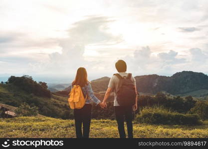 Happy young couple traveler relaxing and looking at the beautiful sunset on the top of mountain