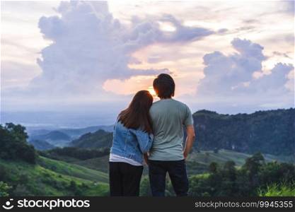Happy young couple traveler relaxing and looking at the beautiful sunset on the top of mountain