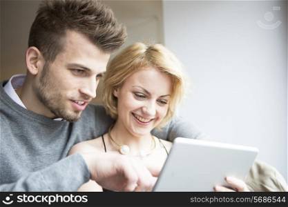 Happy young couple using digital tablet in cafe