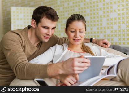 Happy young couple using tablet PC at home