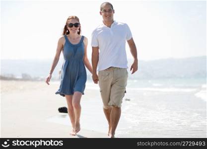 happy young couple walk at the beach