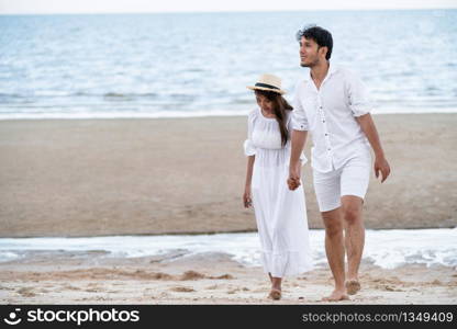 Happy young couple walking on the beach during honeymoon travel vacation.. Happy young couple walk on the beach on honeymoon.