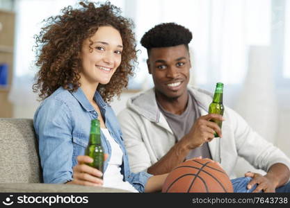 happy young couple watching basketball game on tv at home