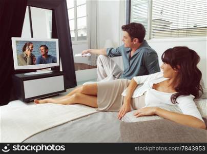 Happy young couple watching television together at home