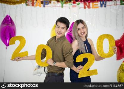 Happy young couple with 2020 balloons on background. New Year celebration