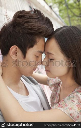 Happy young couple with arms around each other, foreheads touching and eyes closed
