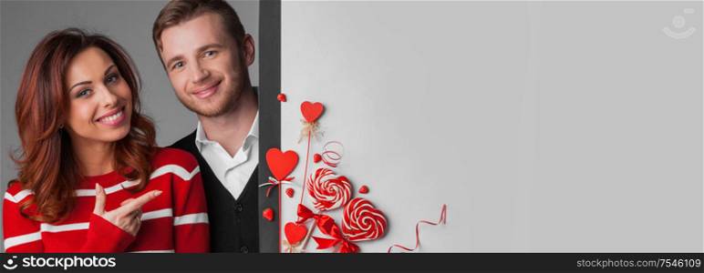 Happy young couple with heart shaped red decoration on white banner background with copy space for text. Valentine&rsquo;s day celebration. Couple with heart red decoration on white