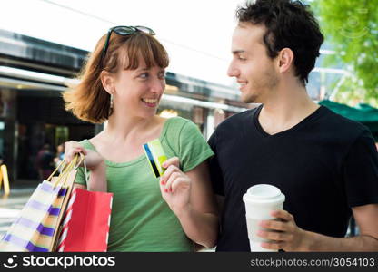 Happy young couple with shopping bags after shopping walking on the streets. Consumerism concept.