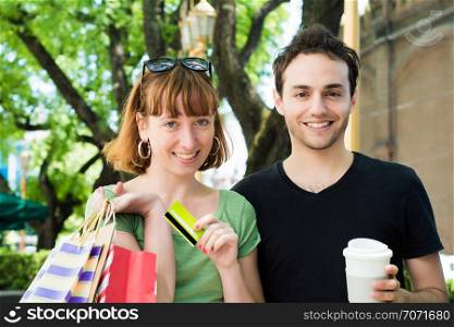 Happy young couple with shopping bags after shopping walking on the streets. Consumerism concept.
