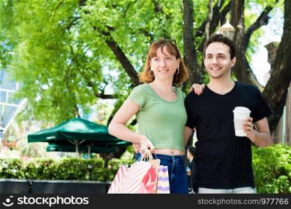 Happy young couple with shopping bags after shopping walking on the streets. Consumerism concept.