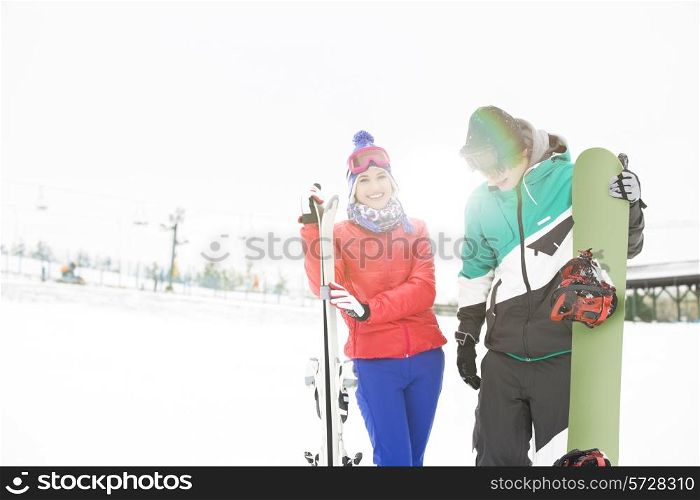 Happy young couple with snowboard and skis in snow