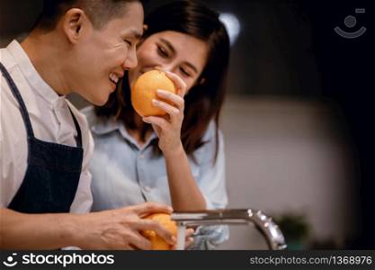 Happy Young Coupple in the Kitchen. Cleaning some Oranges to Preparing Delicious Menu. Cooking Together at Home