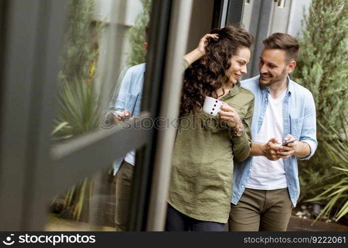 Happy young cute couple in love embracing each other and drinking coffee at home by the window