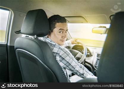 Happy young driver behind the wheel of a car. rear view of a smiling man behind the wheel, rear view of a smiling person sitting behind the wheel, Concept buying a car