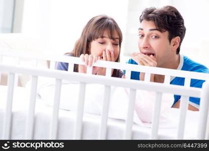 Happy young family at baby bed cot