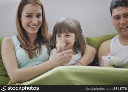 happy young family at home relaxing in bed