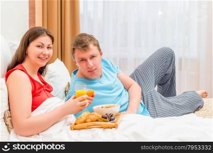 happy young family eating breakfast in bed