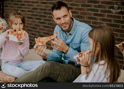 Happy young family eating pizza in the house backyard