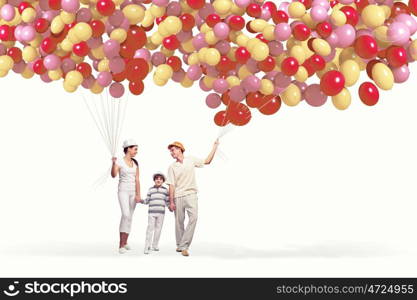 Happy young family. Happy young family walking holding bunch of colorful balloons