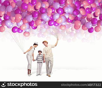 Happy young family. Happy young family walking holding bunch of colorful balloons