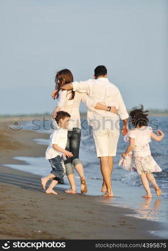 happy young family have fun on beach run and jump at sunset