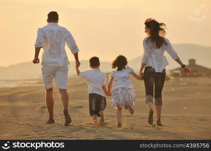 happy young family have fun on beach run and jump at sunset