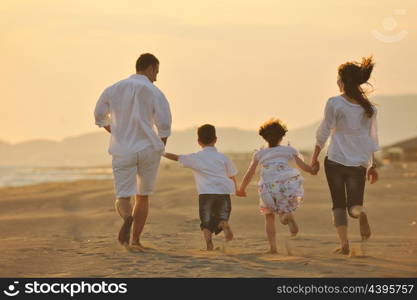 happy young family have fun on beach run and jump at sunset