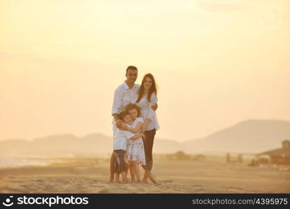 happy young family have fun on beach run and jump at sunset