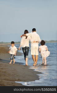 happy young family have fun on beach run and jump at sunset