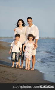 happy young family have fun on beach run and jump at sunset