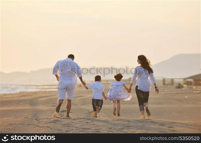happy young family have fun on beach run and jump at sunset