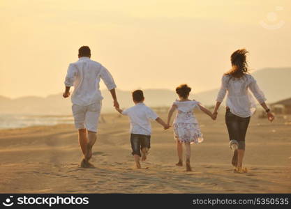 happy young family have fun on beach run and jump at sunset