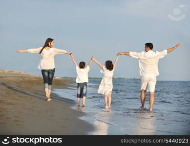 happy young family have fun on beach run and jump at sunset