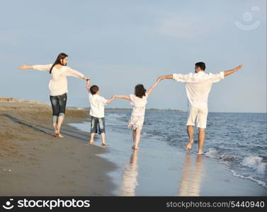 happy young family have fun on beach run and jump at sunset