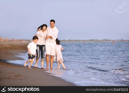 happy young family have fun on beach run and jump at sunset