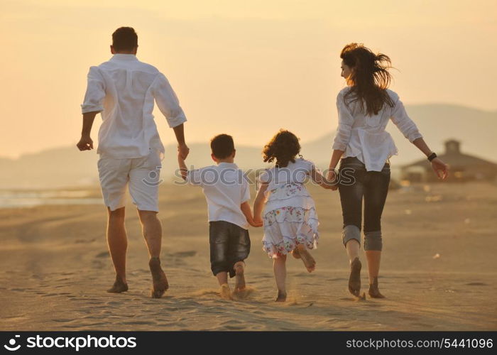 happy young family have fun on beach run and jump at sunset