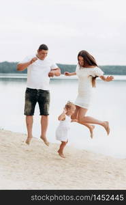 happy young family having fun near the lake, mom dad and daughter playing outdoors. summer holiday, Mother&rsquo;s, father&rsquo;s, baby&rsquo;s day. Spending time together. Family look. happy young family having fun near the lake, mom dad and daughter playing outdoors. summer holiday, Mother&rsquo;s, father&rsquo;s, baby&rsquo;s day. Spending time together. Family look.