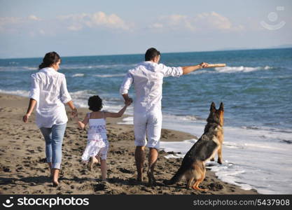 happy young family in white clothing have fun and play with beautiful dog at vacations on beautiful beach