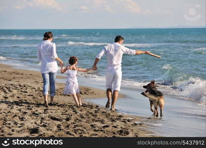 happy young family in white clothing have fun and play with beautiful dog at vacations on beautiful beach