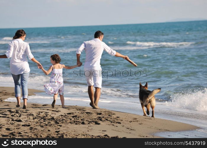 happy young family in white clothing have fun and play with beautiful dog at vacations on beautiful beach