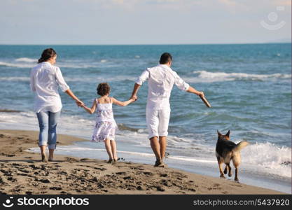 happy young family in white clothing have fun and play with beautiful dog at vacations on beautiful beach