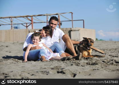 happy young family in white clothing have fun and play with beautiful dog at vacations on beautiful beach