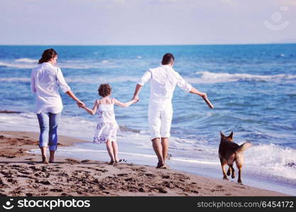 happy young family in white clothing have fun and play with beautiful dog at vacations on beautiful beach